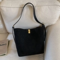 Bolso cubo retro de ante negro con cierre giratorio dorado en un sofá beige - Negro