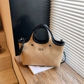 Bolso tote de ante caqui con costuras de diamante y asas negras en un entorno de lujo - Caqui