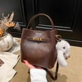 Dunkelbraune Leder-Eimertasche mit goldener Schnalle und Plüschtier-Anhänger - Kaffee mit Anhänger