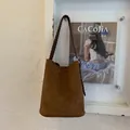 Dettaglio borsa a secchiello in camoscio marrone con tracolla intrecciata e trama retrò - Marrone