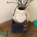 Detailed close-up of a blue suede half-moon bag with brown trim and vintage tassels - Twilight Blue