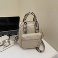 Bolso bandolera beige con correa floral UCHAO sobre escritorio blanco - Beige y negro
