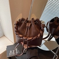 Sac seau en cuir marron foncé avec poignée tressée et fermeture par cordon de serrage - café