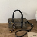 Detail der olivgrünen Wildledertasche mit weißen Kontrastnähten und Web-Anhänger - Grün