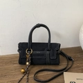 Details der schwarzen Wildlederhandtasche mit weißen Nähten, Goldbeschlägen und Logo - Schwarz