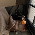 Donkerbruine retro punk schoudertas van glanzend leer met een pluche puppy hanger - koffiekleur