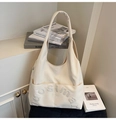 Close-up of cream canvas tote bag with embossed logo and large front pocket detail - Off White