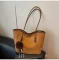 Close-up of brown suede tote bag with MKXQ COEOR embossed logo and pompom tassel detail - With Charm / Yellow Brown