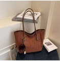 Detail of dark brown suede tote bag with plush charm and MIKO COLOR branding on a chair - With Charm / Brown
