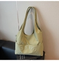 Detail shot of green tote bag showing side pocket and textured embossed logo - Green