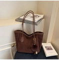 Close-up of deep brown suede tote bag with MIXXO COLOR logo and fuzzy pompom charm - With Charm / Coffee