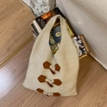 Détail d'un sac cabas en tricot avec boutons à bascule sur un fond en bois cosy - Blanc