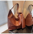 Detail of dark brown faux leather hobo bag with matching detachable pouch on a desk - Caramel Brown