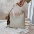 White pebbled leather shoulder bag with decorative tassel and plush charm accessory - Oatmeal