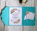 Detailed set of blue pocket wedding invitations with floral RSVP cards on grey wood - Teal Blue