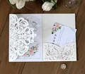 Detalle de invitación de boda cortada con láser con inserto floral sobre madera rústica - Marfil