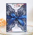 Detail of laser-cut invitation with navy blue satin bow on a decorative gold-rimmed plate - Magic Blue
