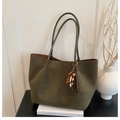 Detailed macro view of olive green suede tote bag featuring a wooden bead tassel charm - Green with Pendant
