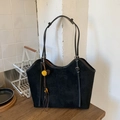 Detalle de bolso tote de ante negro con colgante floral amarillo y cuentas de madera en mesa - Negro con colgante