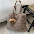 Detail of plush tote bag with woven straps and a cute croissant charm on white rug - Coffee with Pendant