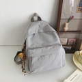 Zaino minimalista in nylon grigio chiaro con ciondolo a nappa in un ambiente accogliente - Con Ciondolo / Grigio