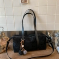 Detalle de bolso tipo almohada en ante negro con cremalleras y colgantes de pompones - Negro con colgante
