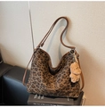 Close-up of leopard print tote bag with brown leather straps and a plush bear charm - Green with Pendant