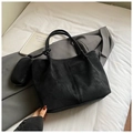 Détail du sac cabas noir avec petite pochette ronde posé sur une veste grise - Noir