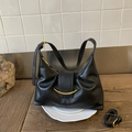 Detail of black semi-moon hobo bag with gold hardware on white ceramic plate - Black