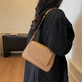 Minimalistische khakifarbene Leder-Schultertasche mit strukturierter Klappe am Modell - Khaki
