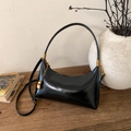 Dettaglio della borsa hobo in pelle verniciata nera con catena d'oro su tavolo - Nero