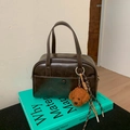 Dettaglio della borsa bowling vintage marrone scuro con finiture dorate e ciondolo - Caffè con Ciondolo