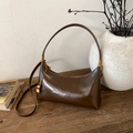 Dettaglio della borsa a spalla in pelle marrone vintage con finiture dorate su legno - Marrone