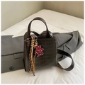 Detail of dark brown crocodile embossed leather handbag with charm and tassel - Coffee
