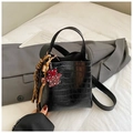Detailed macro of black crocodile embossed bucket bag with red leopard bear charm - Black