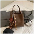 Detail view of brown crocodile texture leather bucket bag with leopard bear charm - Brown