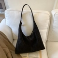 Detalle de bolso hobo de ante marrón oscuro en un sofá con estilo acogedor - Café Oscuro