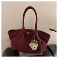 Close-up of a burgundy suede tote bag featuring a plush charm and woven tassel detail - With Pendant / Red