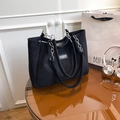 Sac fourre-tout noir avec chaîne argentée et logo sur une table marron élégante - Noir