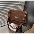 Detalle de bolso retro marrón con cadena dorada y acabado de piel con textura mate - café