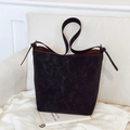Retro black matte bucket bag with wide strap displayed on a white leather sofa - Black