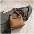 Brown lychee-textured bucket bag with top handle and metal twist lock on white bedding - Brown No Pendant