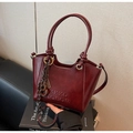 Detailed macro view of burgundy vintage leather bucket bag with embossed logo and metal rings - Wine Red With Pendant