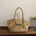 Minimalist large khaki suede tote bag with slim handles and flap detail on wood table - Khaki