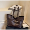 Detail of a dark brown vintage tote bag with adjustable straps on a plush blue chair - Coffee