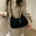 Black hobo crossbody bag with silver buckle and matte suede texture shown on model - Black