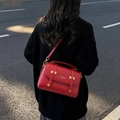 Vintage red lychee pattern leather messenger bag with gold buckle on model outdoors - Red