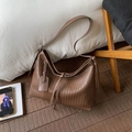 Borsa hobo marrone in pelle intrecciata con tracolla larga in un ambiente accogliente - Marrone