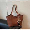 Primer plano del bolso tote retro marrón con logo grabado y colgante de conejo en libros - Con Colgante / Marrón