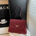 Detail einer dunkelroten Trapez-Handtasche mit strukturierter Oberfläche und Goldverschluss - Rot